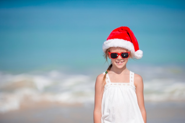 Urocza mała dziewczynka w Santa kapeluszu na tropikalnej plaży