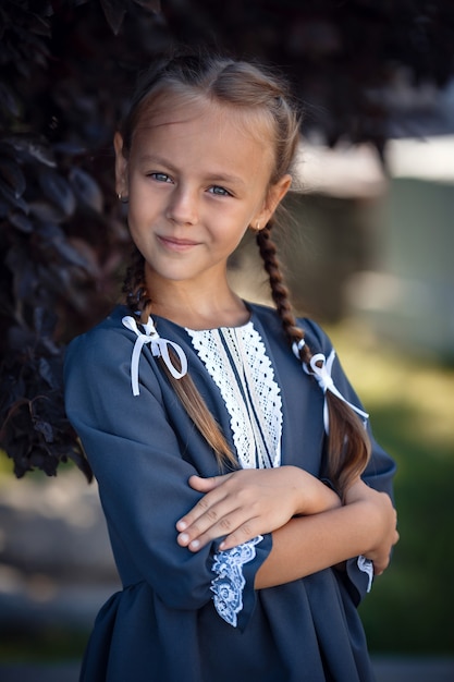 Zdjęcie urocza mała dziewczynka w sukience retro spaceru po mieście w słoneczny letni dzień. mała dziewczynka nosić mundurek szkolny.