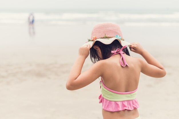 Urocza mała dziewczynka w swimsuit pozyci przy tropikalną plażą