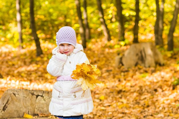 Urocza mała dziewczynka z jesiennych liści w parku