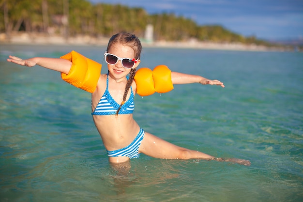 Urocza mała dziewczynka zabawy w morzu na wakacje na tropikalnej plaży