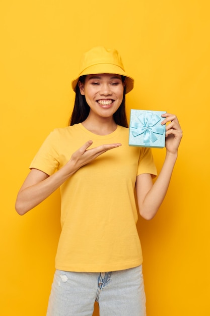 Zdjęcie urocza młoda azjatka w żółtej koszulce i kapeluszu z niezmienionym modelem ze studia prezentów