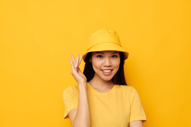 Urocza młoda azjatycka kobieta w żółtym kapeluszu pozuje emocje monochromatyczne ujęcie