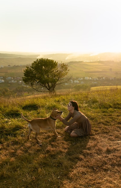 Urocza młoda dziewczyna bawi się biegając ze swoim słodkim psem na naturze podczas zachodu słońca