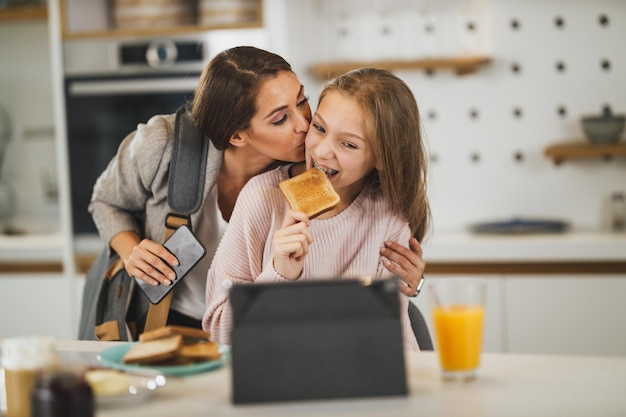 Urocza nastolatka i jej uśmiechnięta matka witają się w swoim domu, podczas gdy mama przygotowuje się do pracy.