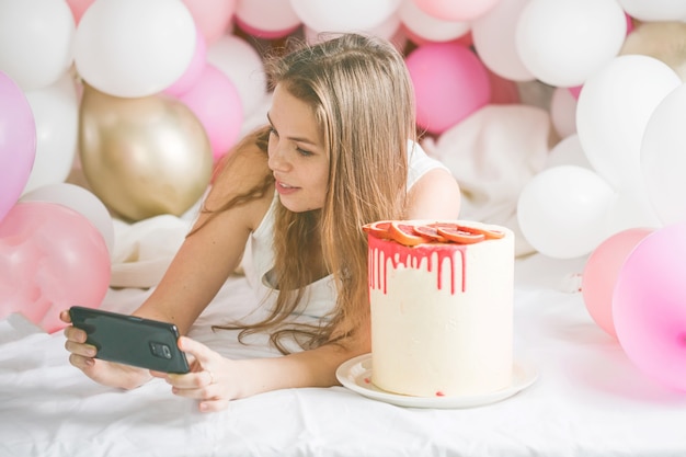 Urocza pani w piżamie co selfie w jej sypialni przy użyciu telefonu