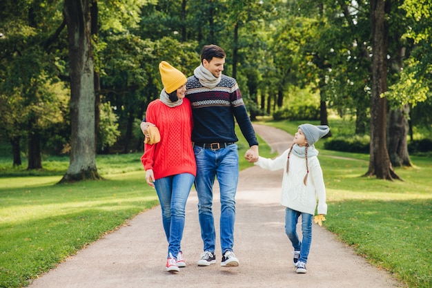 Urocza Para Obejmuje Się, Patrzy Na Swoją Małą, Dobrze Wyglądającą Córkę, Idzie Przez Zielony Park