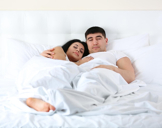 Urocza para śpi w białym łóżku