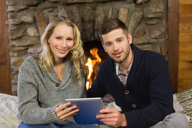 Urocza para za pomocą tabletu PC przed oświetlonym kominkiem