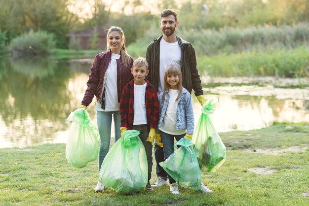 Urocza Rodzina Rodziców I Dzieci Trzyma Plastikowe Worki Na śmieci Po Sprzątaniu Okolicy W Pobliżu Jeziora