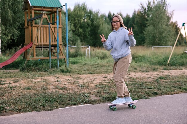 Urocza szczęśliwa dziewczyna jeździ na deskorolce w parku