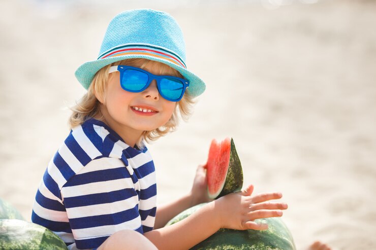 Zdjęcie urocze dziecko na brzegu morza, jedzenie soczystego arbuza. rozochocony dziecko na lato czasie na plaży. ładny mały chłopiec na zewnątrz