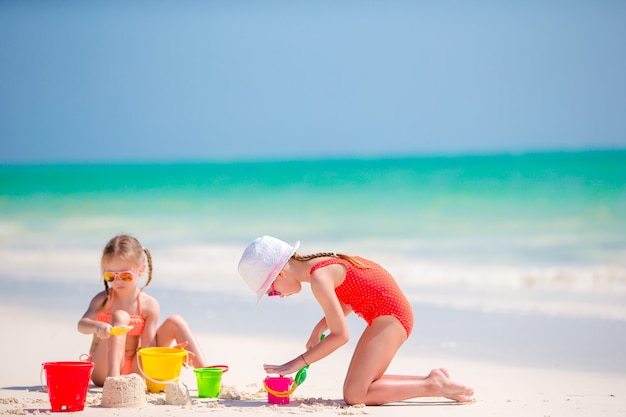 Urocze dziewczynki podczas letnich wakacji. Dzieci bawiące się zabawkami na plaży na białej plaży