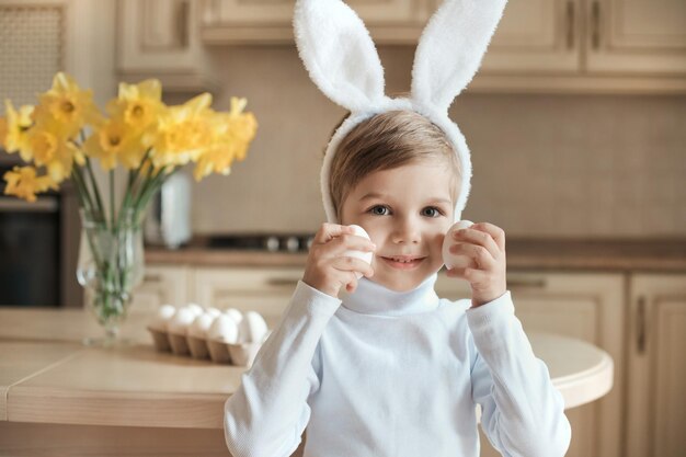 Zdjęcie uroczy dziecko w zabawnych uszach królików bawi się jajkami i jest gotowe na wielkanoc