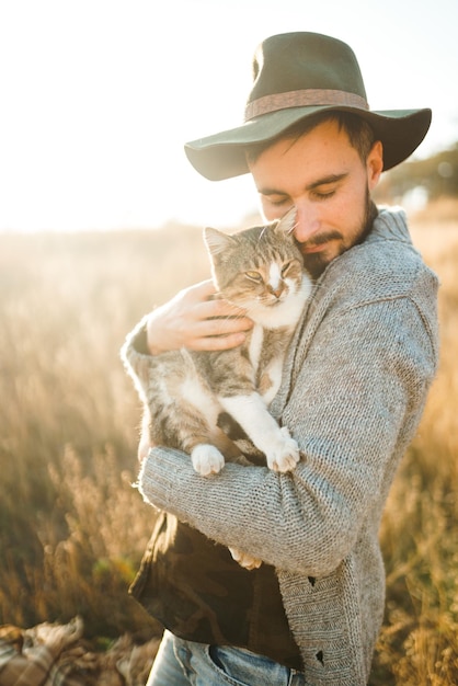 Uroczy młody hipster z kotem Facet z wąsem i pięknym uśmiechem przytula kota