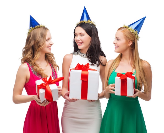 uroczystość, przyjaciele, wieczór panieński, koncepcja urodzinowa - trzy uśmiechnięte kobiety w niebieskich czapkach z pudełkami na prezenty