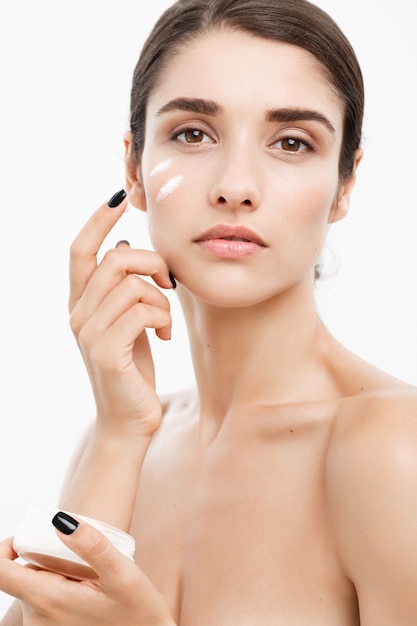 Uroda Młodzież Skin Care Concept - Zamknij w górę Piękne Kaukaski Kobieta Twarz Portret stosowania śmietany na twarz do pielęgnacji skóry. Pi? Kny model Spa Dziewczyna z Perfect Fresh Czystość skóry na białym tle.