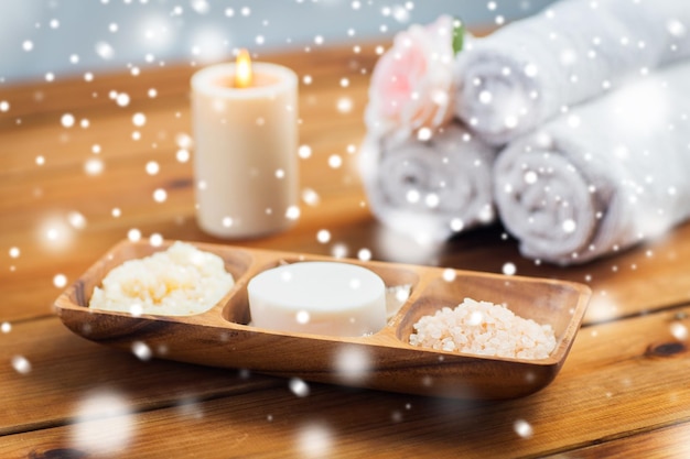 uroda, spa, pielęgnacja ciała, kosmetyki naturalne i koncepcja kąpieli - mydło kosmetyki naturalne sól himalajska i peeling w drewnianej misce na stole nad śniegiem
