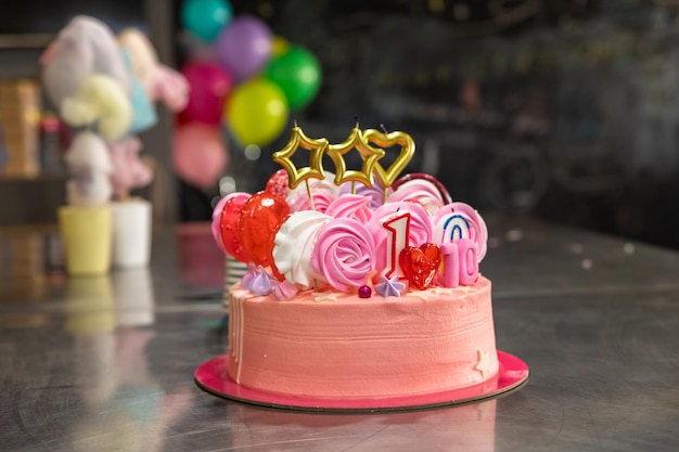 Urodziny tło z różowym tortem urodzinowym z lizakami beza świece kolorowe balony