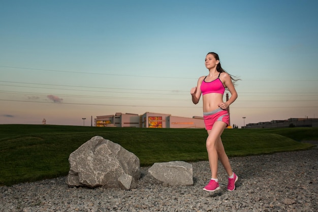 Uruchomiona kobieta. Biegacz jogging w słonecznej przyrodzie. Model fitness kobiece szkolenia poza w tle zachodu słońca niebo.