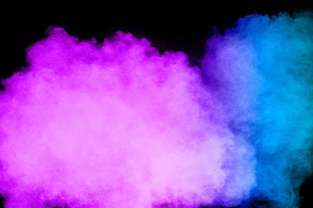 Uruchomiono rozpryskujące się niebiesko-różowe cząstki pyłu Dziwaczne formy chmury eksplozji niebiesko-różowego proszku na białym tle