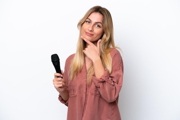 Urugwajska piosenkarka podnosi mikrofon odizolowany na białym tle szczęśliwy i uśmiechnięty