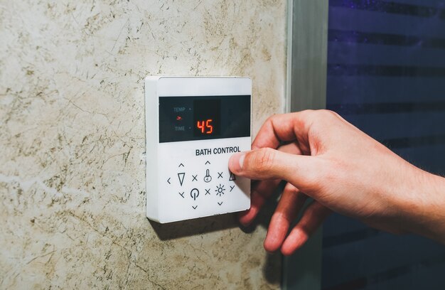 Urządzenie sterujące łaźnią parową w saunie. Człowiek reguluje palcami temperaturę w hamamie. Czas wolny i koncepcja relaksu.