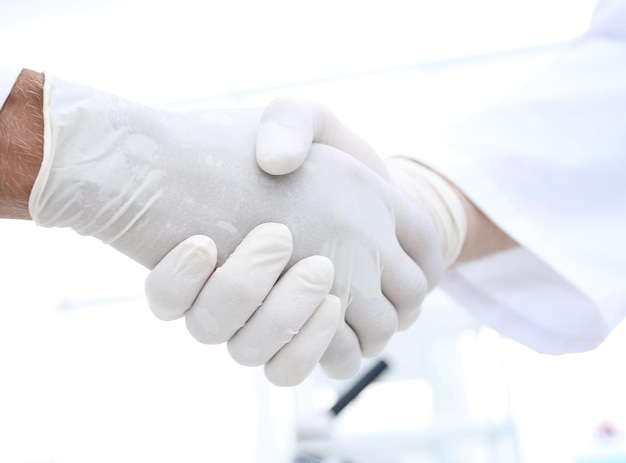 Uścisk dłoni w białych rękawiczkach medycznych