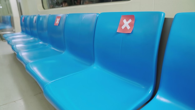 Usiądź w publicznym podziemnym metrze ze znakami ostrzegającymi o zachowaniu odległości jednego miejsca w celu ochrony przed rozprzestrzenianiem się COVID-19