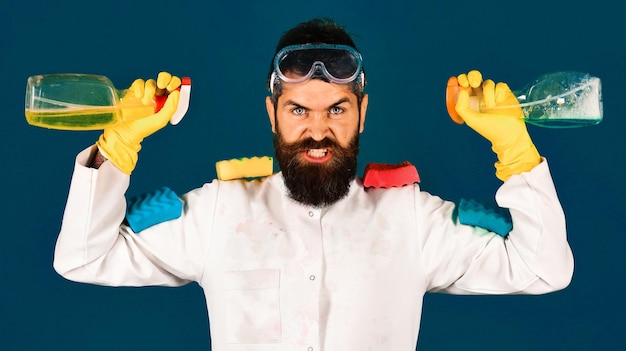 Zdjęcie usługa sprzątania brodaty mężczyzna z gąbkami i detergentem w sprayu reklamującym środki czyszczące