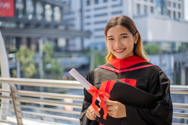 Uśmiech azjatyckiego studenta absolwenta ręki trzymającej dyplom