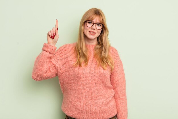 Uśmiecha się wesoło i radośnie, wskazując w górę jedną ręką, aby skopiować przestrzeń