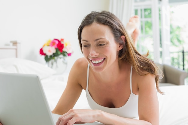 Uśmiechać Się Zrelaksowanej Kobiety Używa Laptop W łóżku