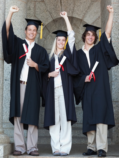 Uśmiechnięci absolwenci podnosi rękę