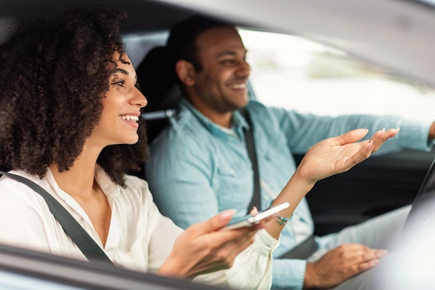 Uśmiechnięci arabscy małżonkowie używający telefonu komórkowego do nawigacji w nowym samochodzie