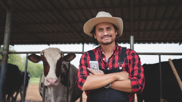Uśmiechnięci i szczęśliwi rolnicy uzyskują dochód z gospodarstwa mleczarskiego Przemysł rolniczy Koncepcja hodowli i hodowli zwierząt Krowa na farmie mlecznej jedząca siano Obora