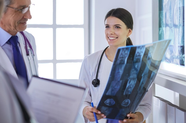 Uśmiechnięci lekarze omawiają diagnozę pacjenta patrząc na zdjęcia rentgenowskie w szpitalu