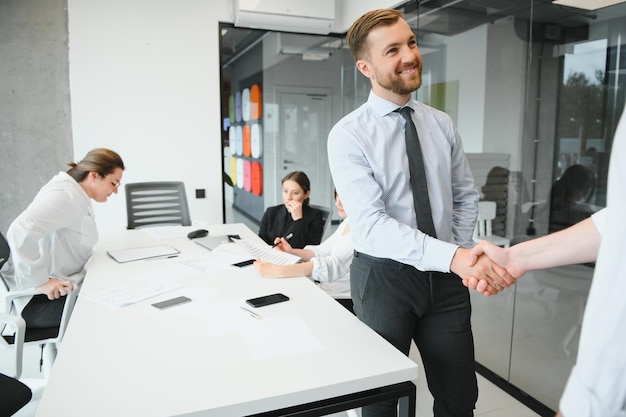 Uśmiechnięci męscy partnerzy biznesowi negocjatorzy uścisk dłoni start grupowe biuro negocjacyjne przedstawiciele firmy powitanie uścisk dłoni na spotkaniu zapoznanie się z szacunkiem zawarcie transakcji finansowej