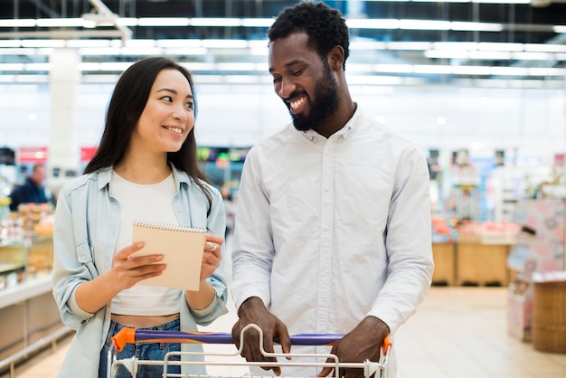 Uśmiechnięci multiethnical pary kupienia towary w supermarkecie