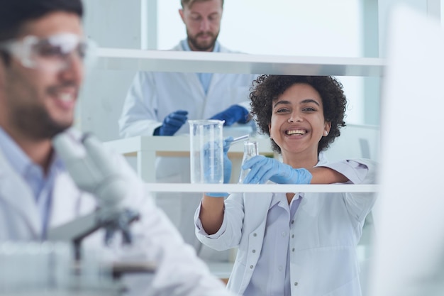 Uśmiechnięci naukowcy patrzący na ramiona aparatu skrzyżowane w laboratorium