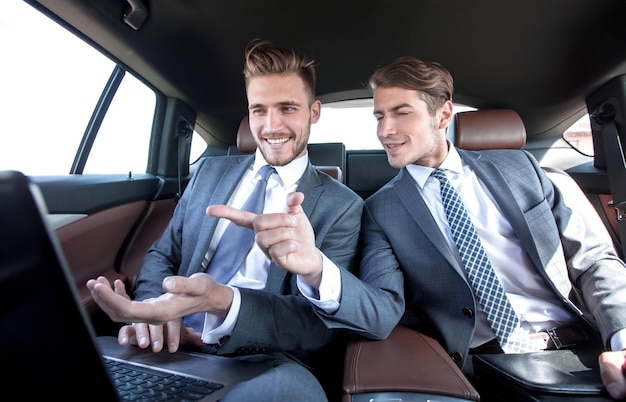 Uśmiechnięci partnerzy biznesowi patrzący na ekran laptopa