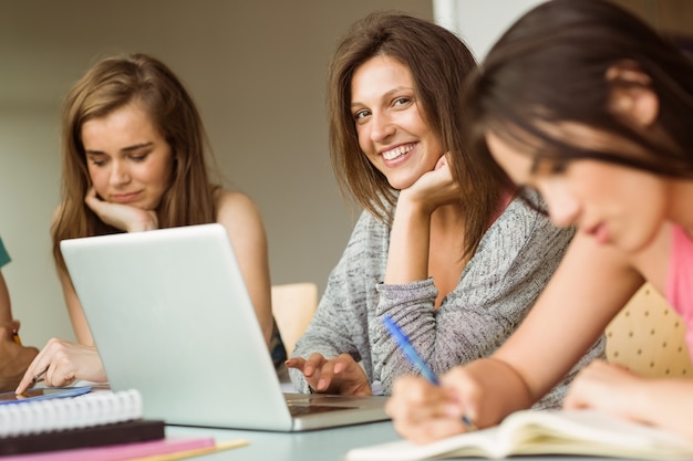 Zdjęcie uśmiechnięci przyjaciele siedzi studiować i używa laptop