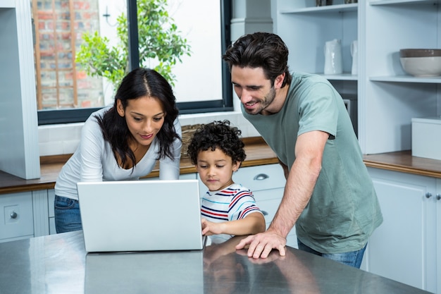 Uśmiechnięci rodzice używa laptop z synem
