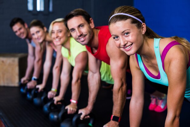 Uśmiechnięci sportowcy ćwiczy z kettlebells