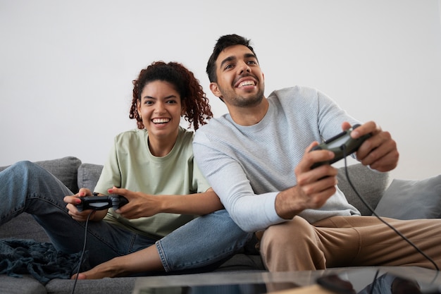 Uśmiechnięci współlokatorzy grający w gry wideo, widok z przodu