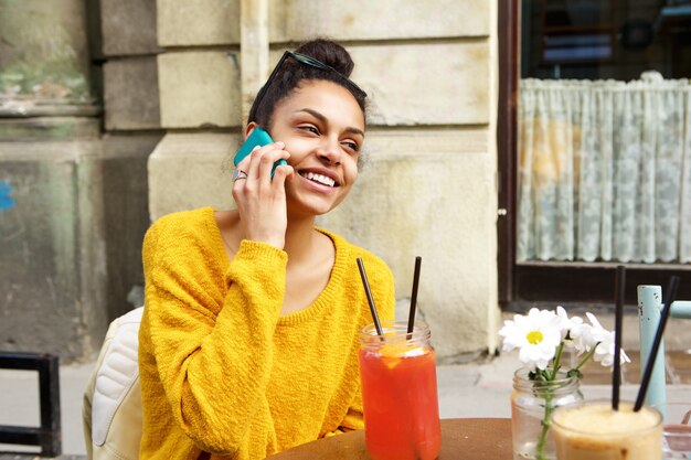 Uśmiechnięta afrykańska kobieta przy coffeeshop robi rozmowa telefonicza