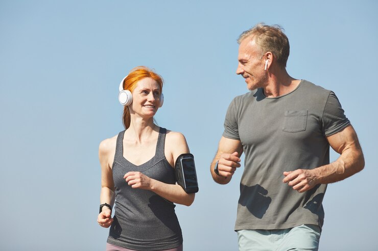 Zdjęcie uśmiechnięta atrakcyjna ruda kobieta z opaską, ciesząc się joggingu z chłopakiem rano