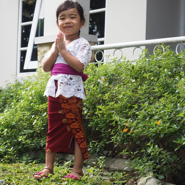 Zdjęcie uśmiechnięta azjatycka dziewczyna w balijskich tradycyjnych kostiumach pokazująca pozycję modlitwy ręcznej