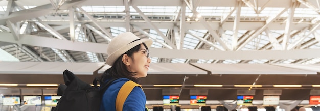 Zdjęcie uśmiechnięta azjatycka kobieta czeka blisko odprawy w kontuarze na lotniskowym wyjściowym terminal.