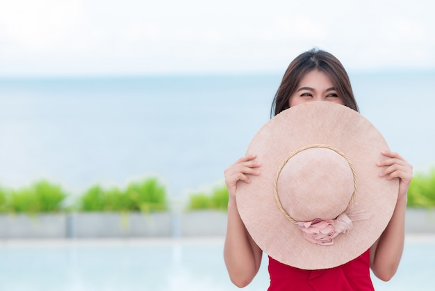Uśmiechnięta Azjatycka kobiety nakrycia twarz z round kapeluszem